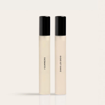 Two rectangular perfume bottles with black caps and cream-colored liquid labeled "7 Summers" and "Dawns Les Bois".