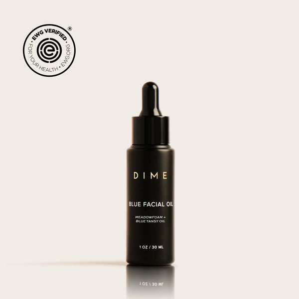 Black dropper bottle labeled "DIME Blue Facial Oil" with 30ml capacity on beige background.