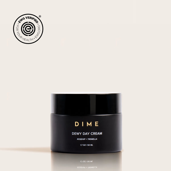 Black jar labeled "DIME Dewy Day Cream" with gold text, 1.7 oz, featuring EWG Verified seal.