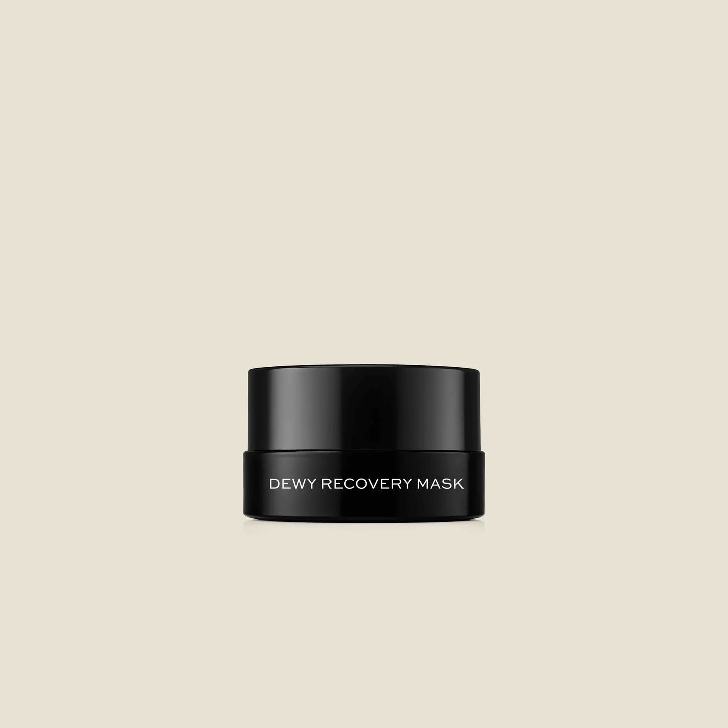 Black jar with white text reading "Dewy Recovery Mask" against a beige background.