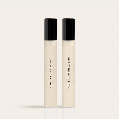 Two cream-colored fragrance bottles with black caps labeled "I LOVE YOUR SMELL BABY"