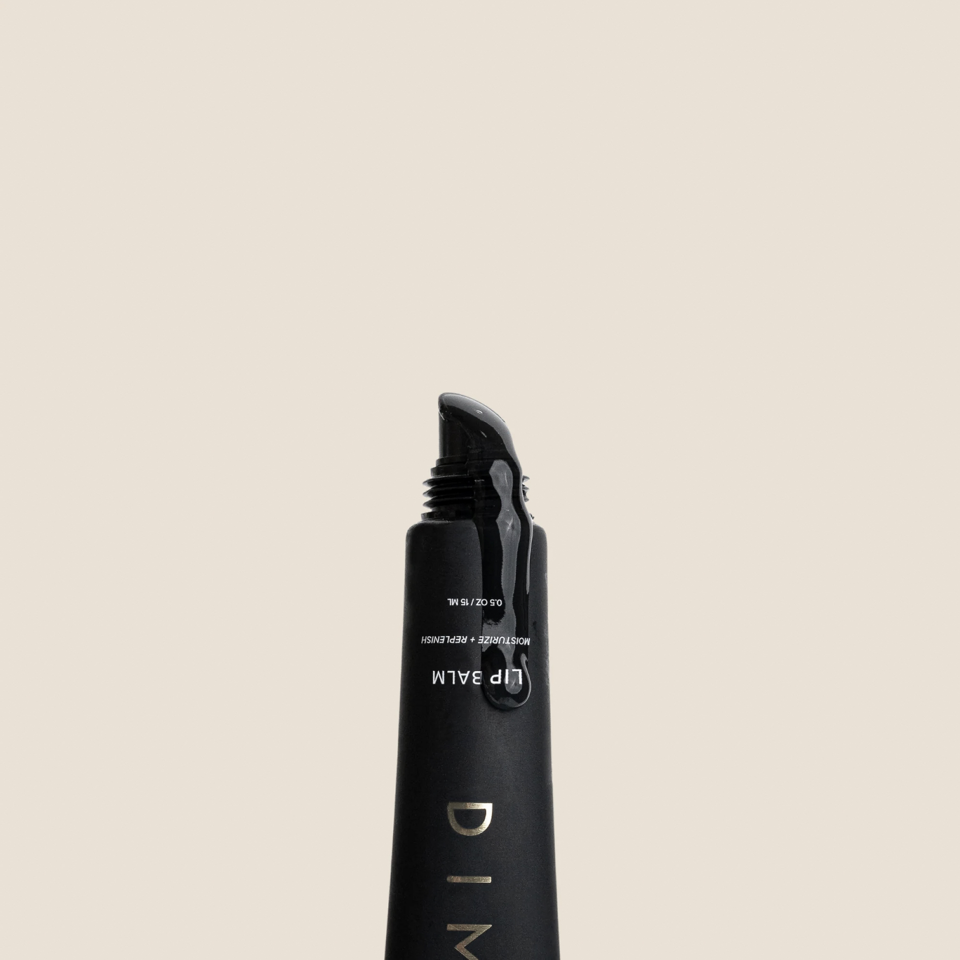 Black cylindrical lip balm tube with cap against a beige background, displaying product branding and text.