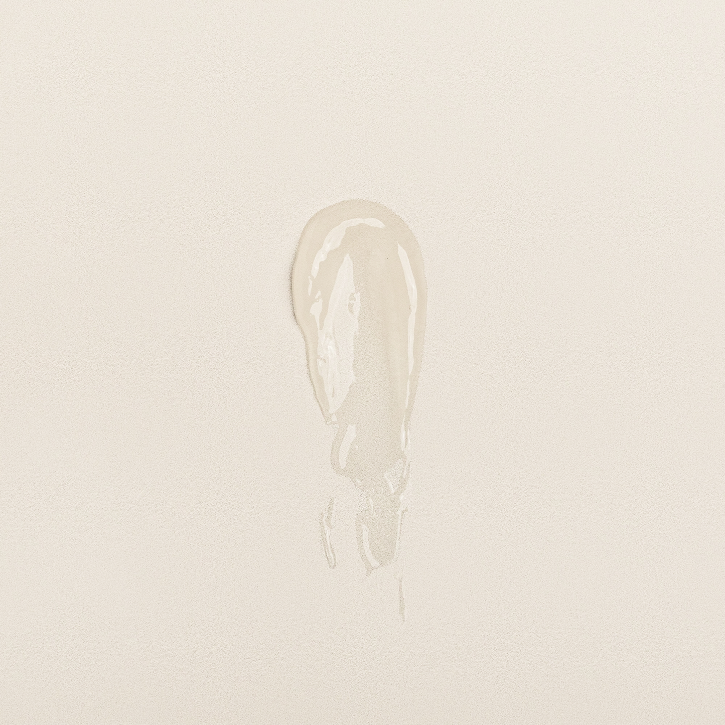Clear lip balm swatch showing creamy, glossy texture on neutral background.