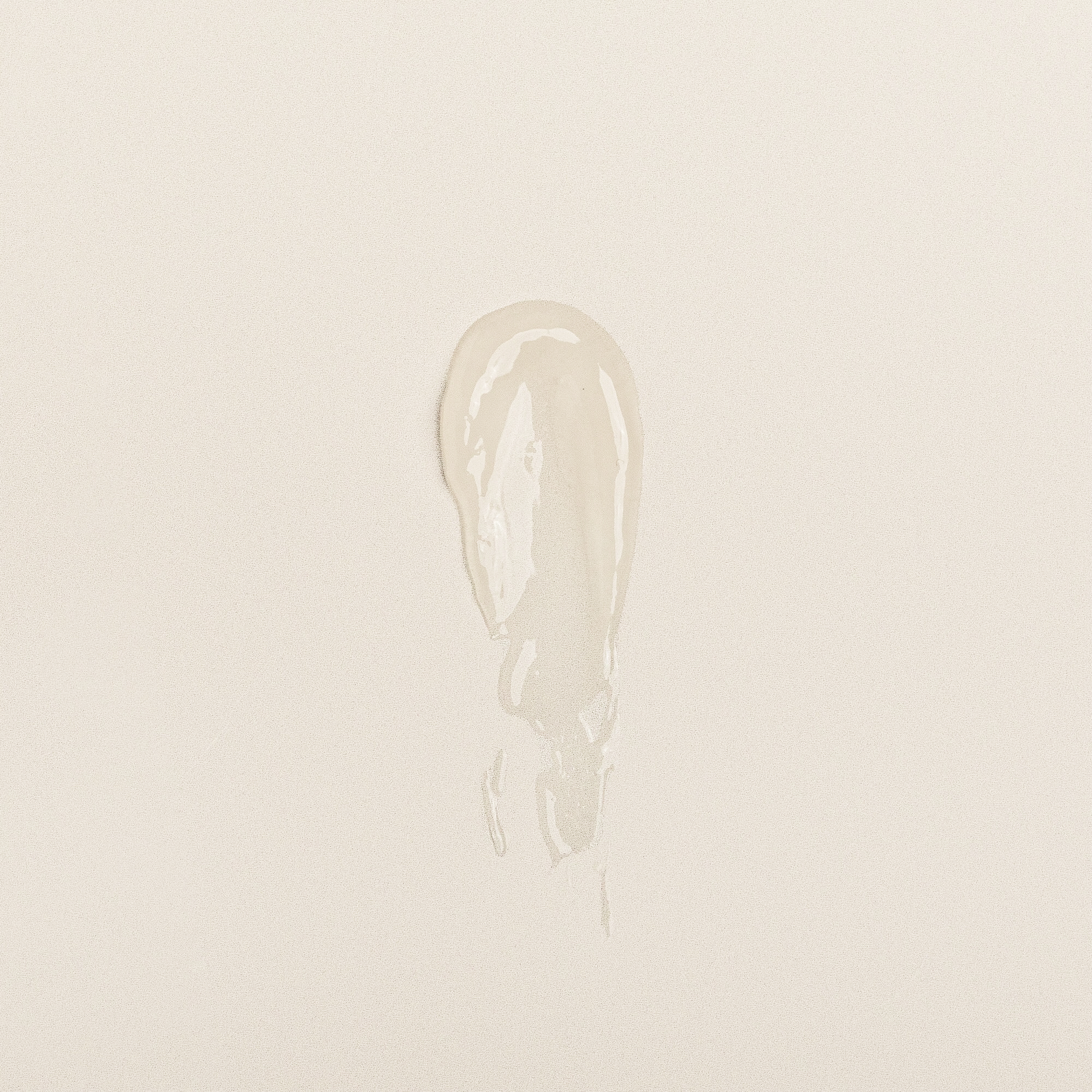 Clear lip balm swatch showing creamy, glossy texture on neutral background.