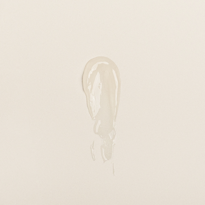 Clear lip balm swatch showing creamy, glossy texture on neutral background.