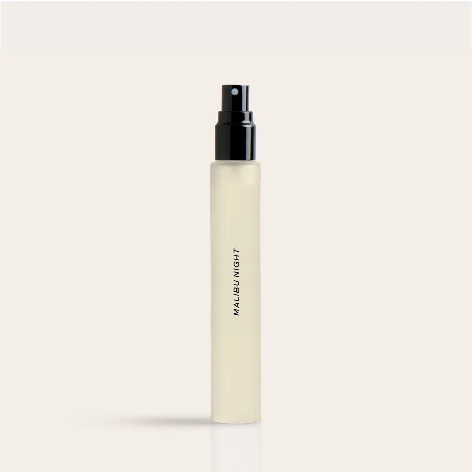 Cylindrical cream-colored perfume spray bottle with black atomizer top and "Malibu Night" text on label.